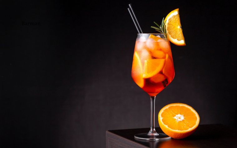 Aperol Spritz podany w kieliszku do wina z plasterkiem pomarańczy i rozmarynem.