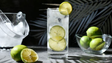 Gin & Tonic podany z limonką i kostkami lodu w wysokiej szklance.
