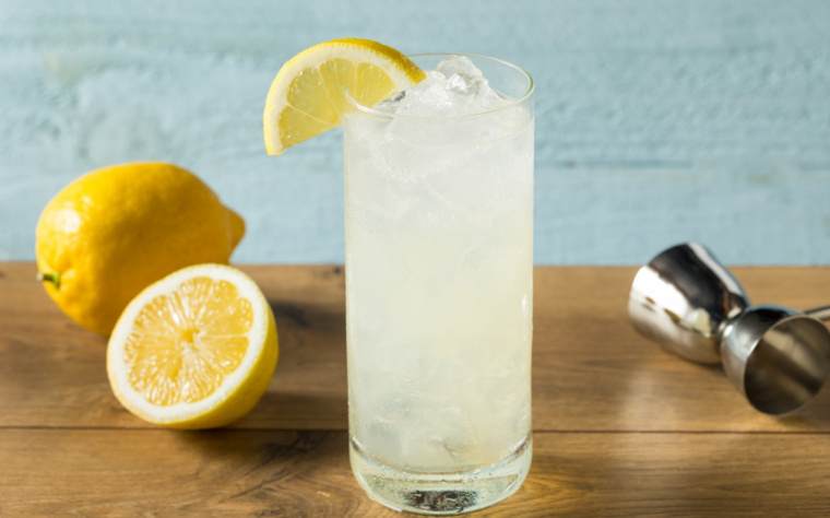 Tom Collins podany w wysokiej szklance z plasterkiem cytryny i kruszonym lodem.